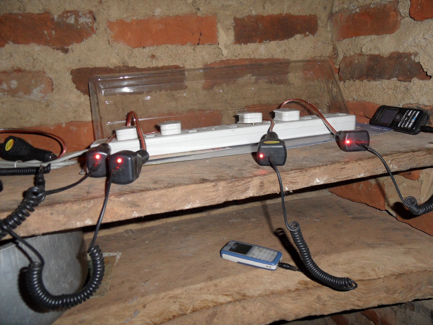 Picture of a bank of basic mobile phones being charged from a six gang adaptor